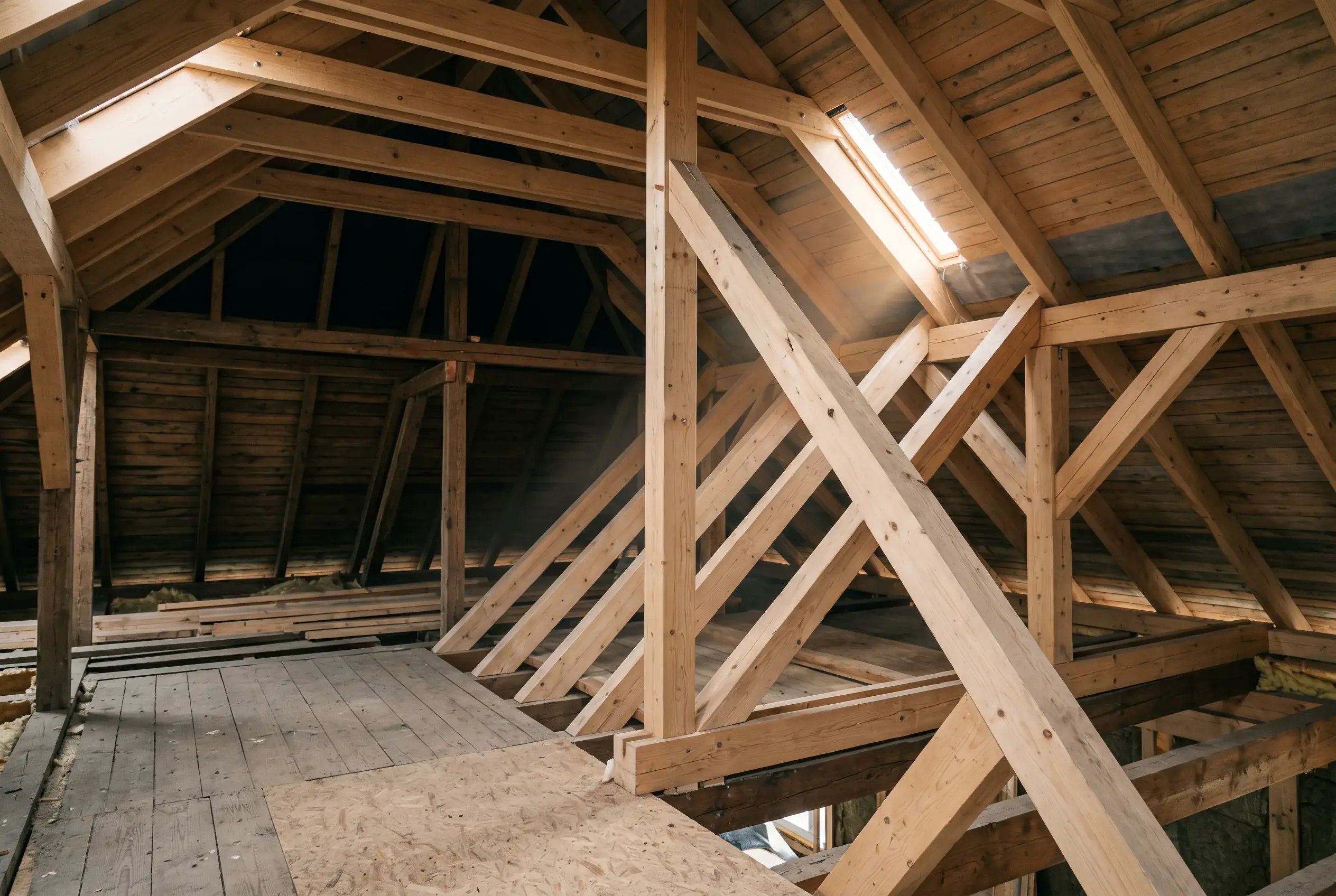 Neuer Dachstuhl aus Holz mit sichtbaren Sparren und Pfetten